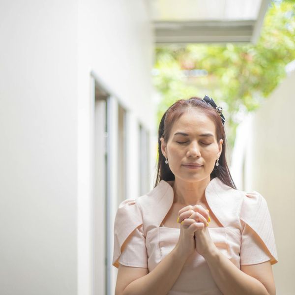 A person meditating peacefully outdoors with a serene natural background.